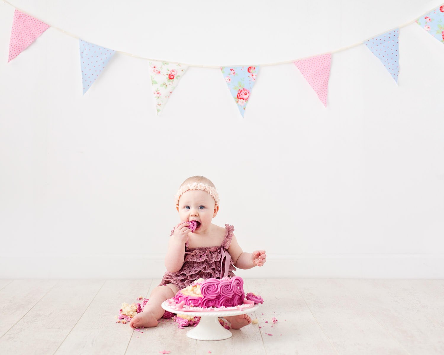 Girl eating cake in pink dress during cake smash photo shoot Glasgow