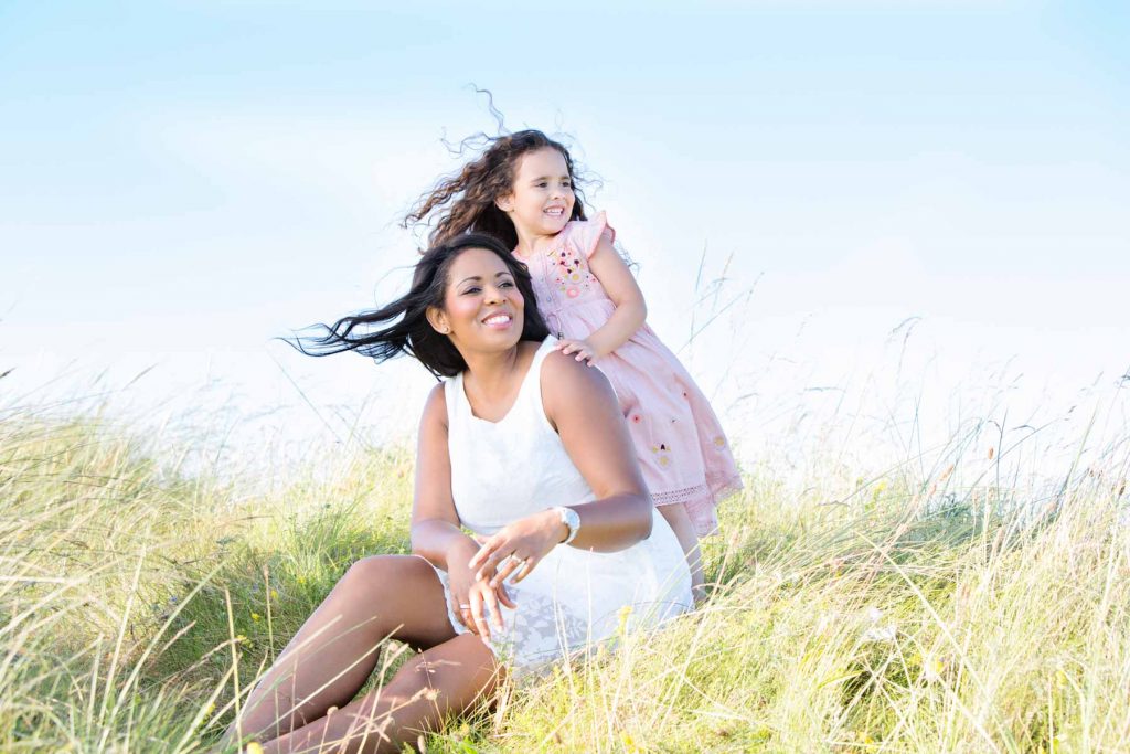 Mother and daughter sitting in sand dunes