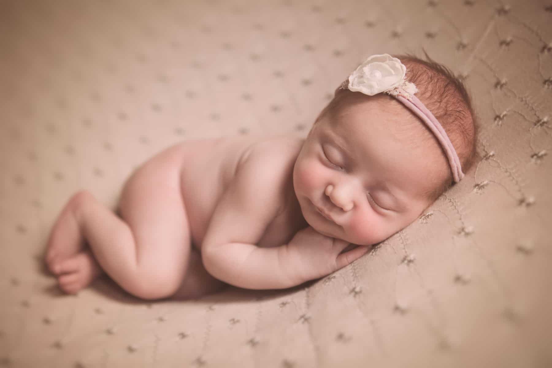newborn baby girl with headband sleeping