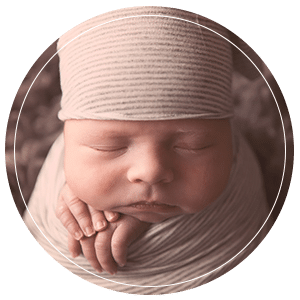 Newborn baby boy swaddled and sleeping wearing a hat.