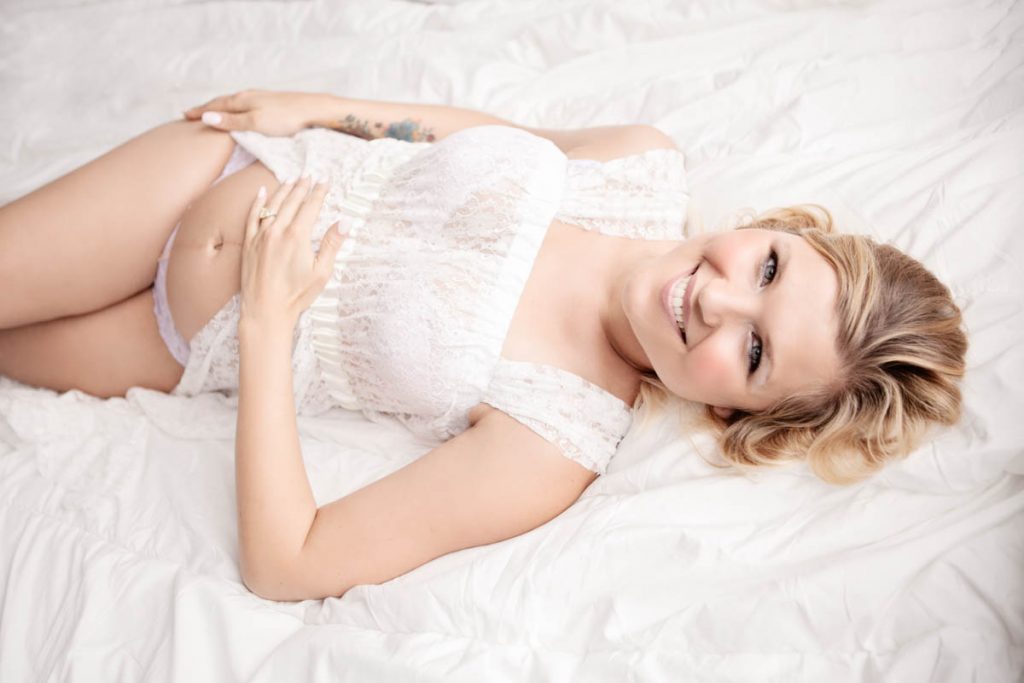 Maternity photography of a woman in white dress smiling