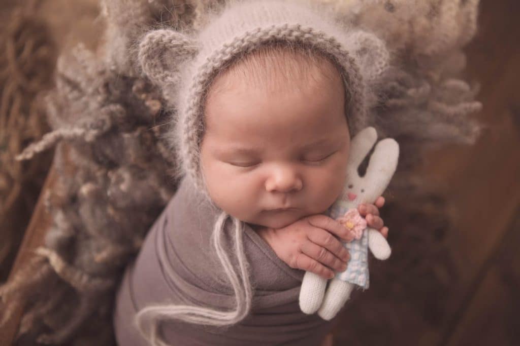 newborn baby girl wearing a teddy bear hat