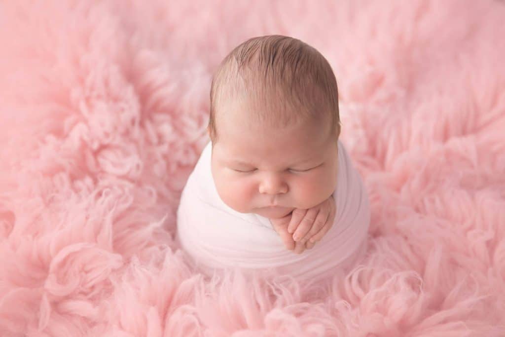 Newborn baby girl on pink flokati rug