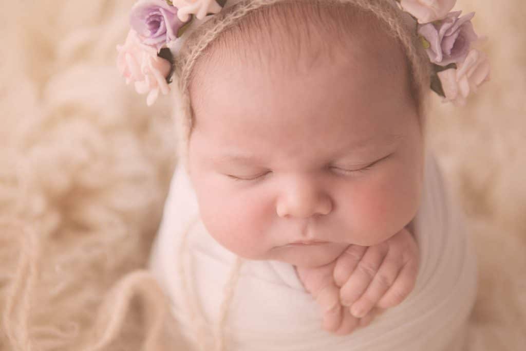 Portrait of newborn baby girl wearing floral hat