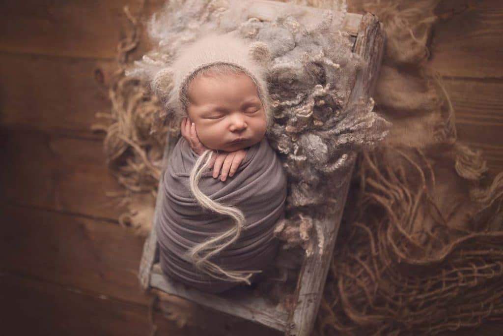 Newborn baby girl sleeping in wooden crate