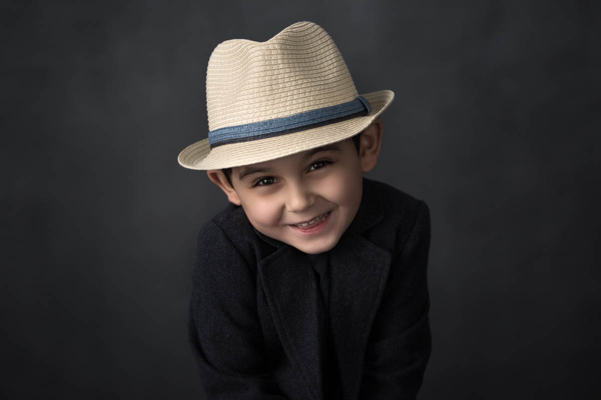 boy wearing fedora hat smiles