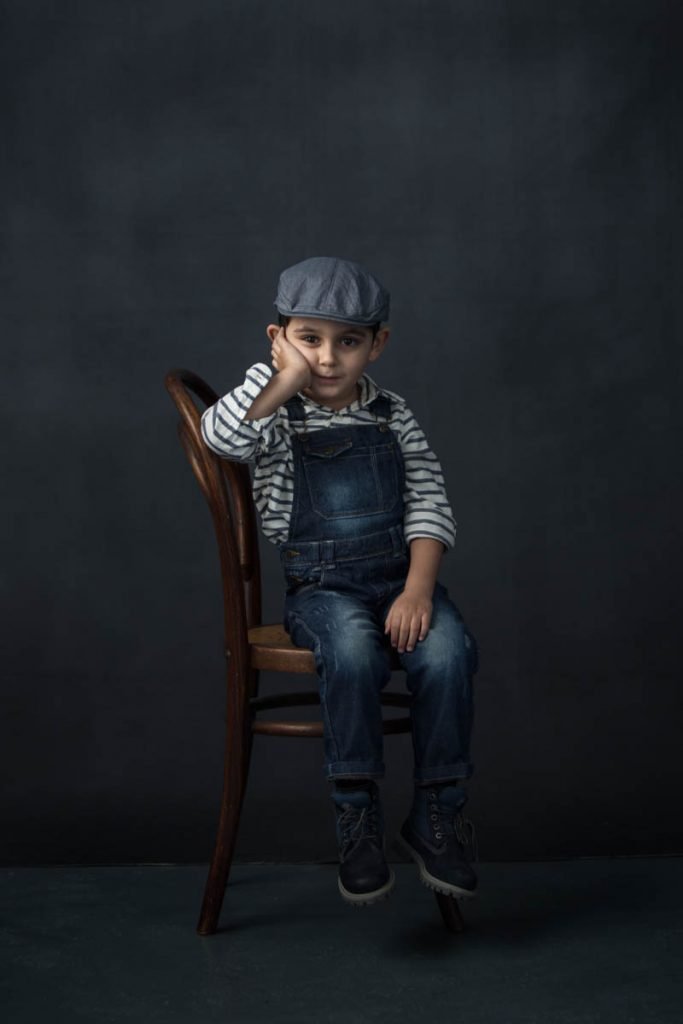 boy wearing denim dungarees in fine art studio portrait